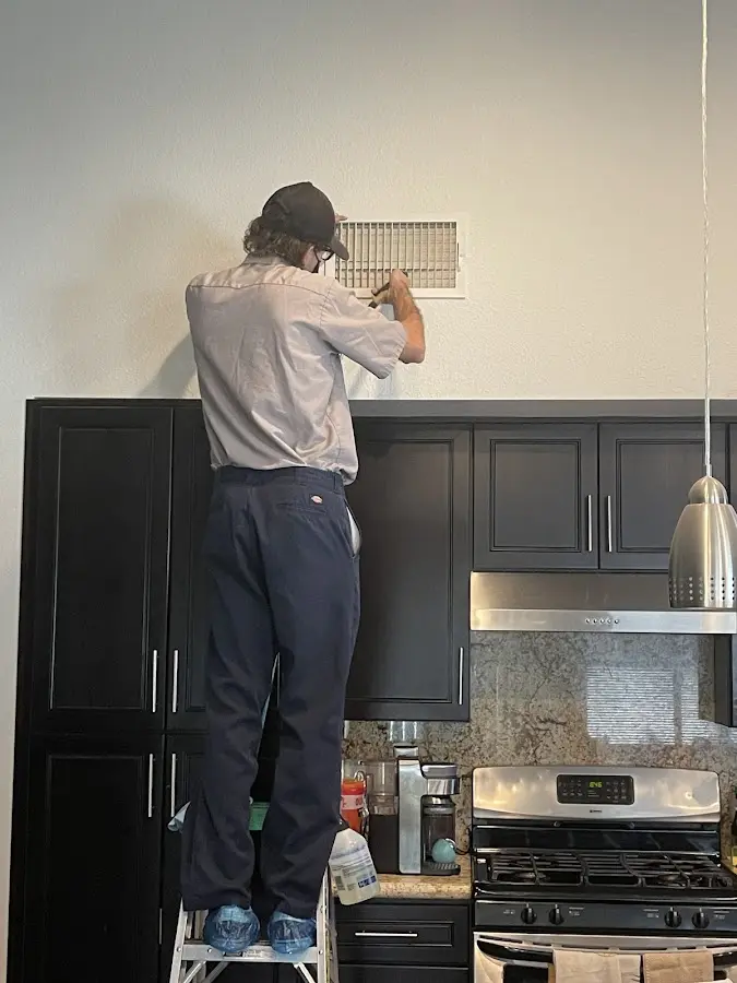 Technician inspecting an air vent during HVAC service in Toledo